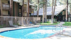 A swimming pool with lounge chairs and a wooden fence. - Sleeps 8 w Loft | 3 Baths, Hot Tub & Tennis (Mammoth Lakes)