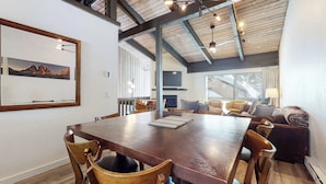 A dining area with a wooden table and chairs, a fireplace, and a large window.
