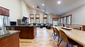 Una cocina amplia con una isla central, una mesa de comedor de madera y una zona de estar acogedora con un sofá y ventanas grandes.