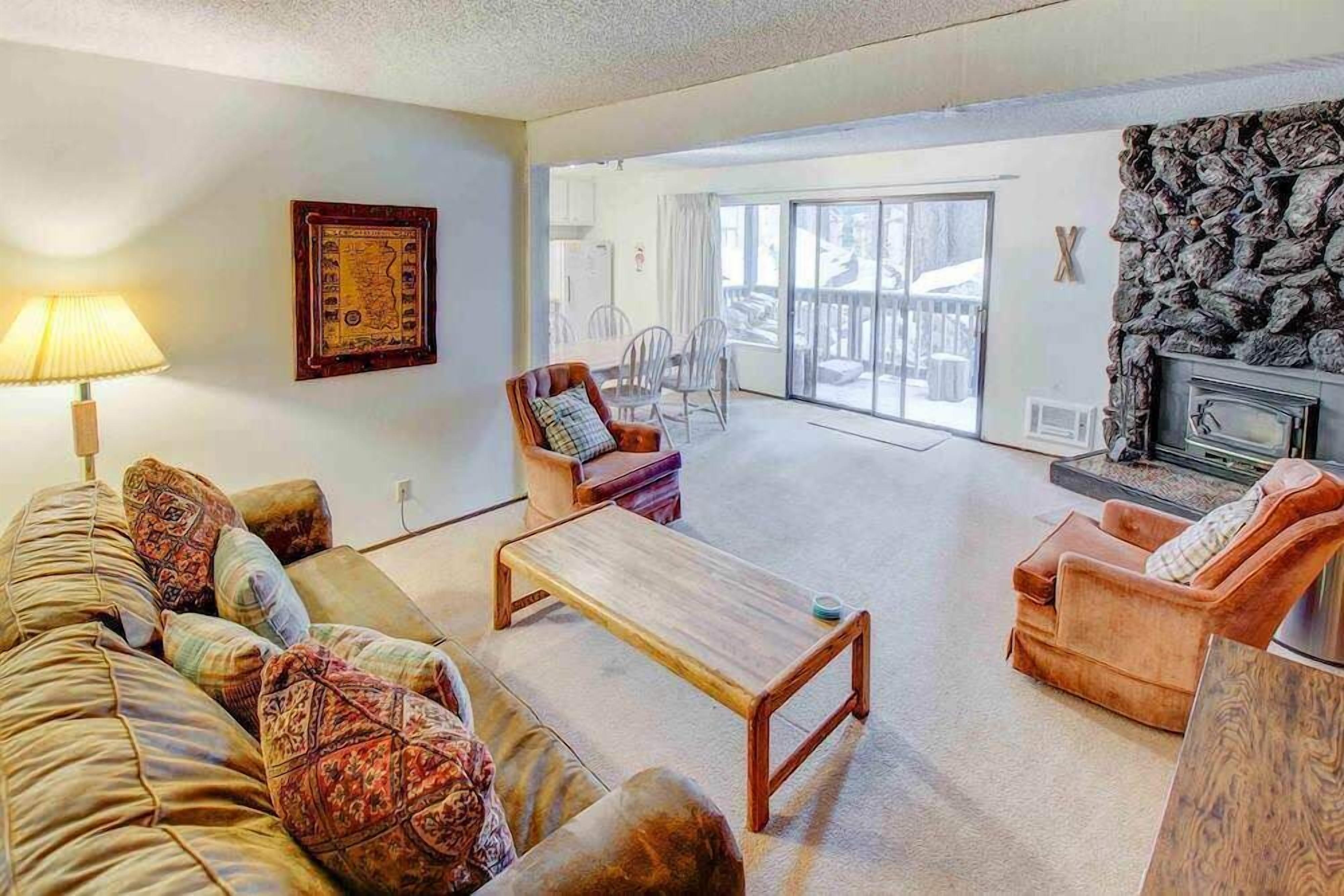 Un salon comprenant un canapé, des fauteuils, une table basse et une cheminée. Il y a également un balcon avec vue sur l’extérieur.