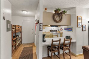 A compact kitchen with a dining area, wooden furniture, and a small herb garden.