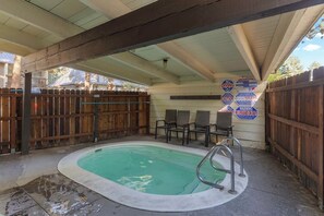 A covered outdoor swimming pool with a wooden fence, a lifeguard stand, and a sign indicating no diving.