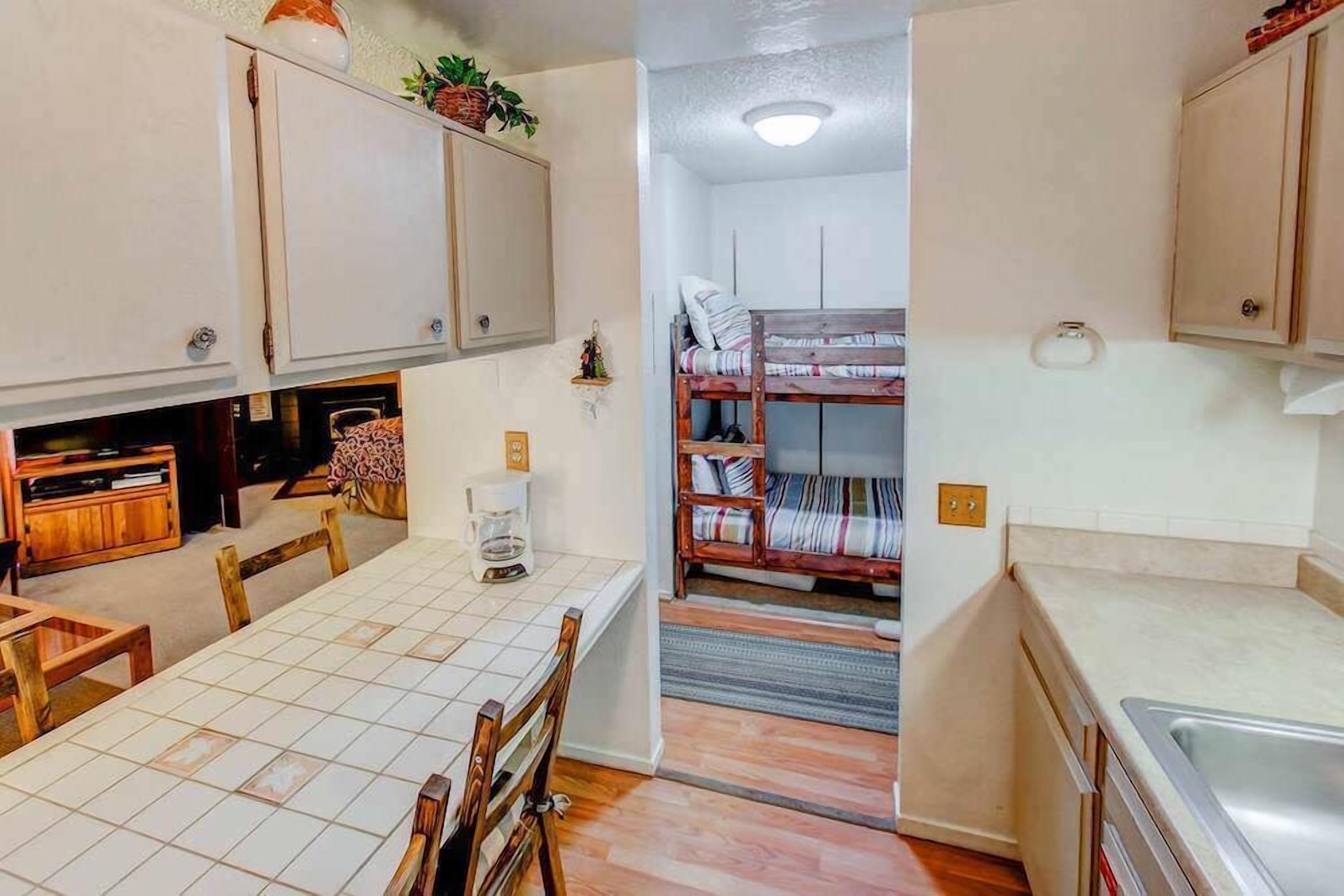 A compact kitchen with a tiled backsplash, wooden cabinets, and a dining area with a table and chairs.