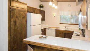 Una cocina con armarios de madera, un refrigerador blanco, un lavavajillas y una isla de madera con un bol.