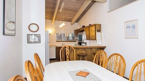 Un comedor con una mesa, sillas y una cocina al fondo.