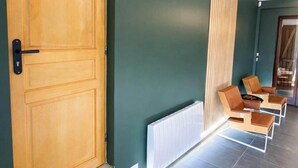 A reception area with a wooden door, a radiator, and a seating area with chairs. - Suite Prestige Spa&Piscine Privée - LikeaDreamRoom (Blennes)