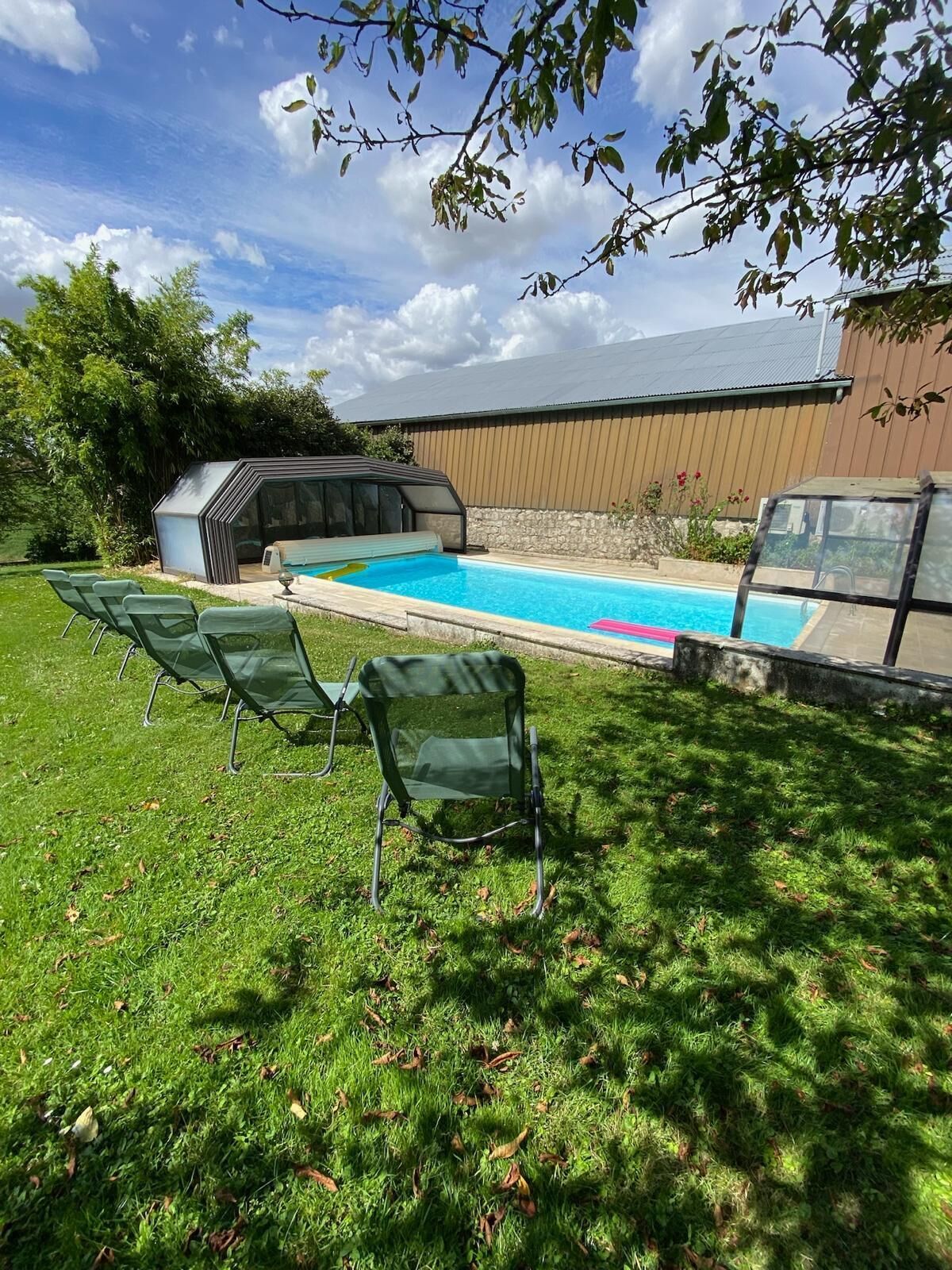 En trädgård med en swimmingpool, en uppvärmd utomhuspool och ett område med grill.