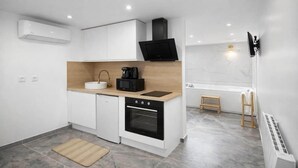 A modern kitchen with white cabinetry, a built-in oven, a coffee maker, and a microwave. - Suite Prestige Spa&Piscine Privée - LikeaDreamRoom (Blennes)