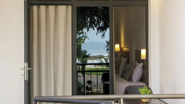 Een balkon met uitzicht op zee, een bank en een tafel met een lamp.
