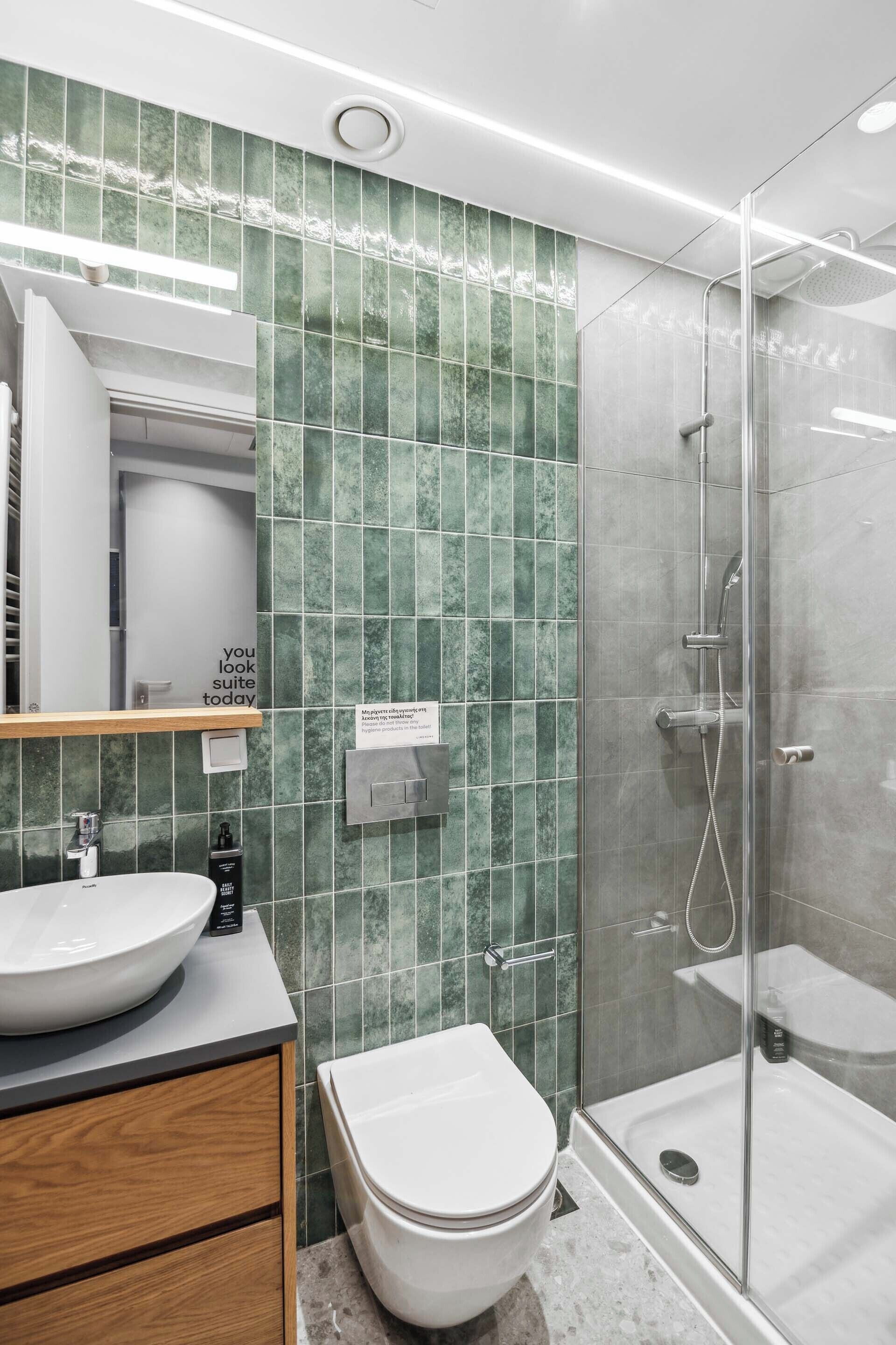 Un baño moderno con lavamanos grande, inodoro y ducha con mampara de vidrio.