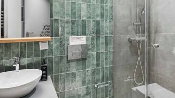 Un baño moderno con lavamanos grande, inodoro y ducha con mampara de vidrio.