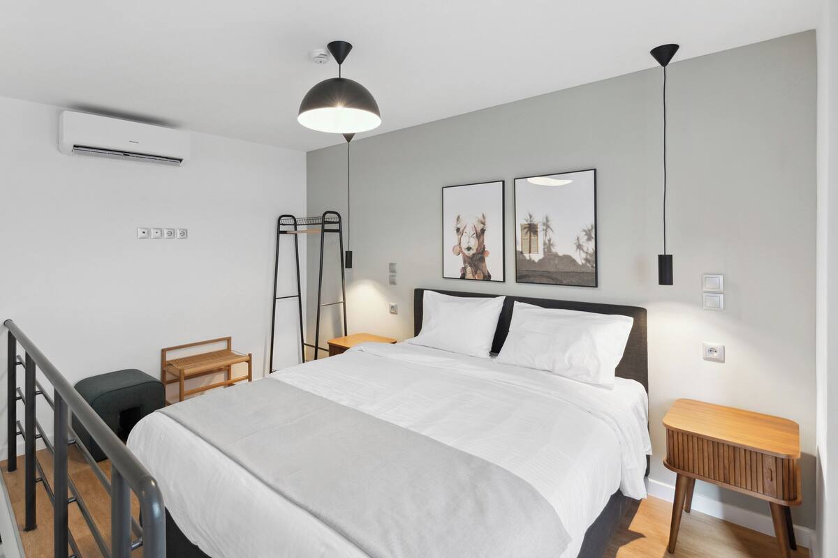 A modern bedroom with a large bed, two bedside tables, a wooden bench, and a ceiling fan.