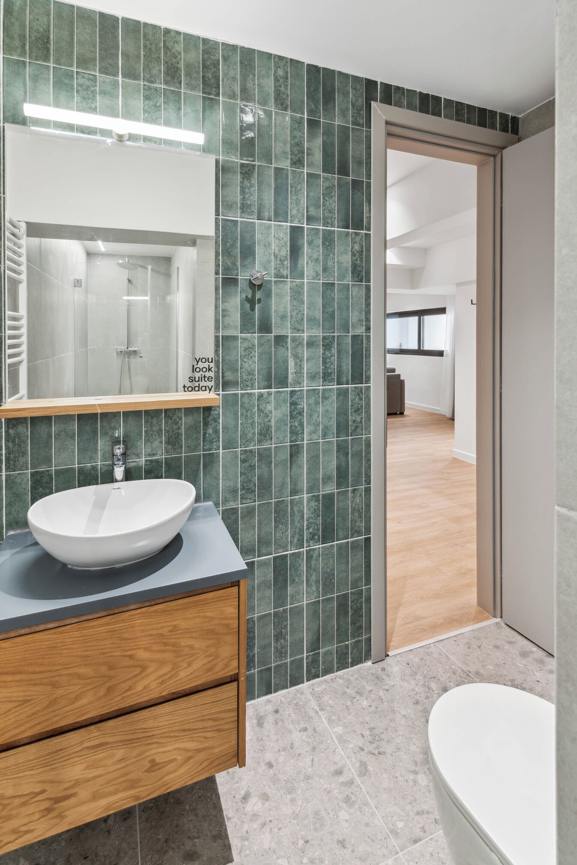 A modern bathroom with a large mirror, a wooden vanity, and a white sink.