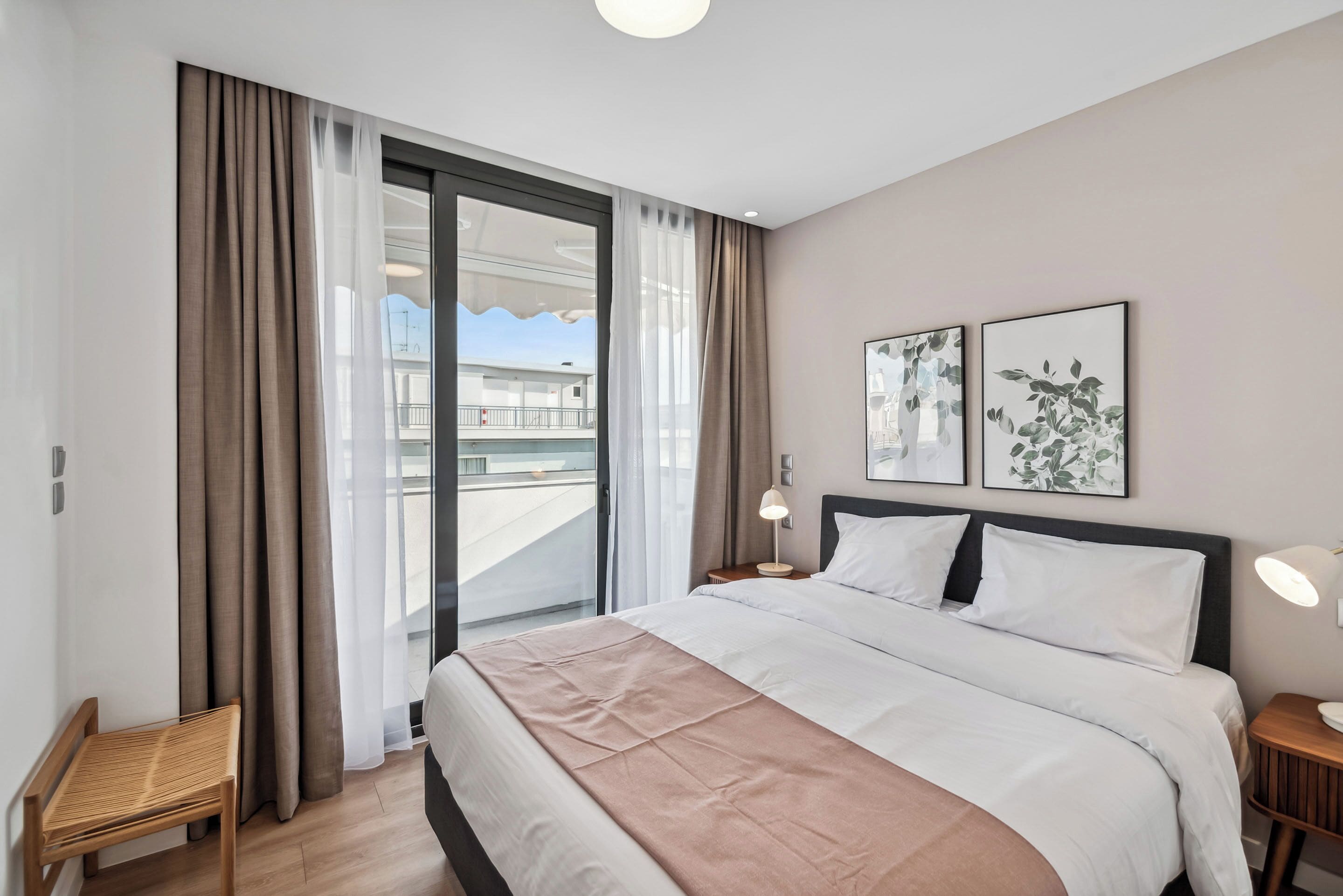 Une chambre d’hôtel moderne, dotée d’un grand lit, d’une petite table, d’une chaise et d’un balcon offrant une vue sur la ville.