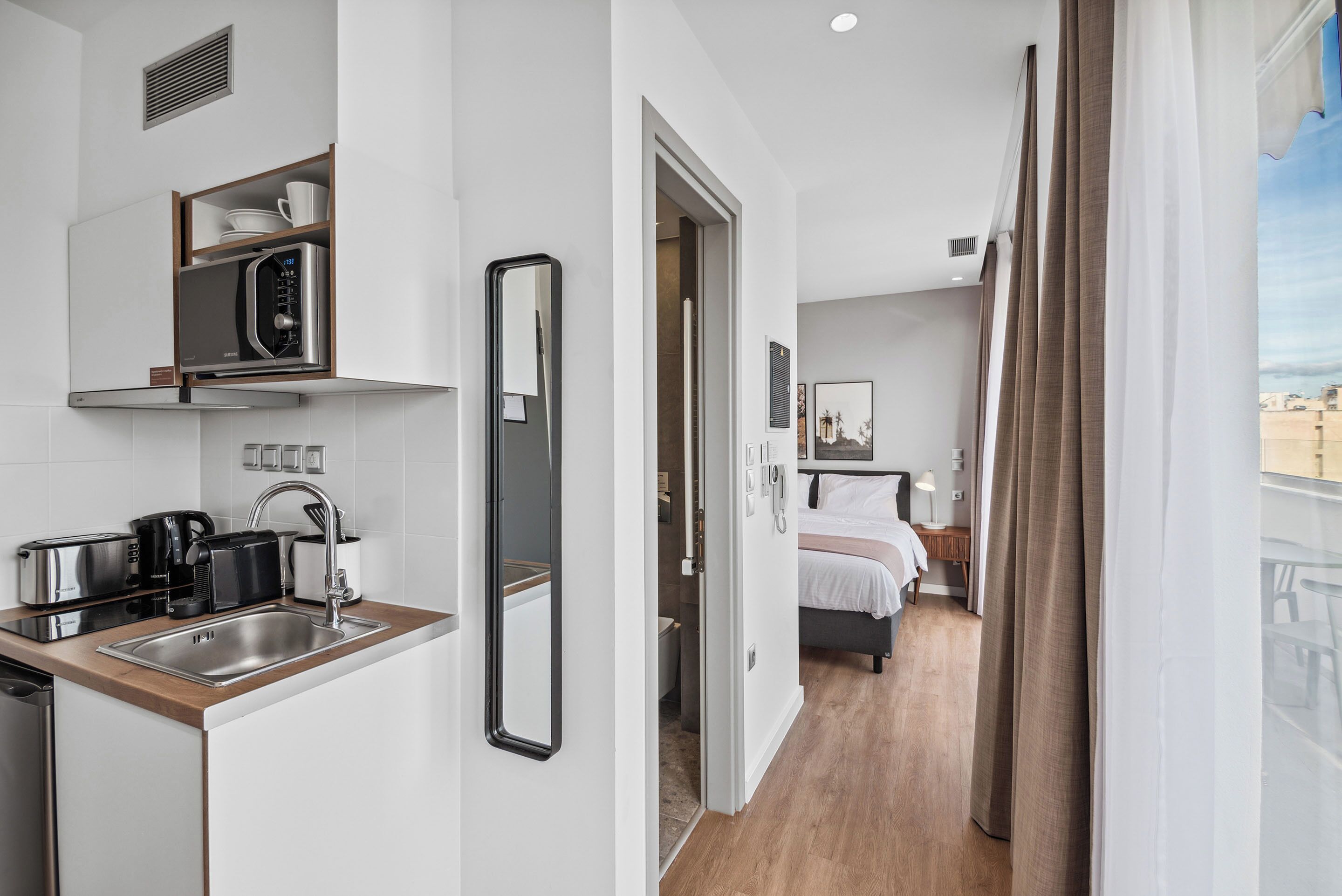 Habitación de hotel compacta con kitchenette, una cama y vista a la ciudad.