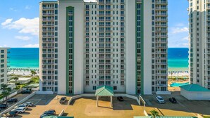 Un hôtel de grande hauteur doté de nombreux balcons, d’un parking et offrant une vue sur la plage et l’océan.