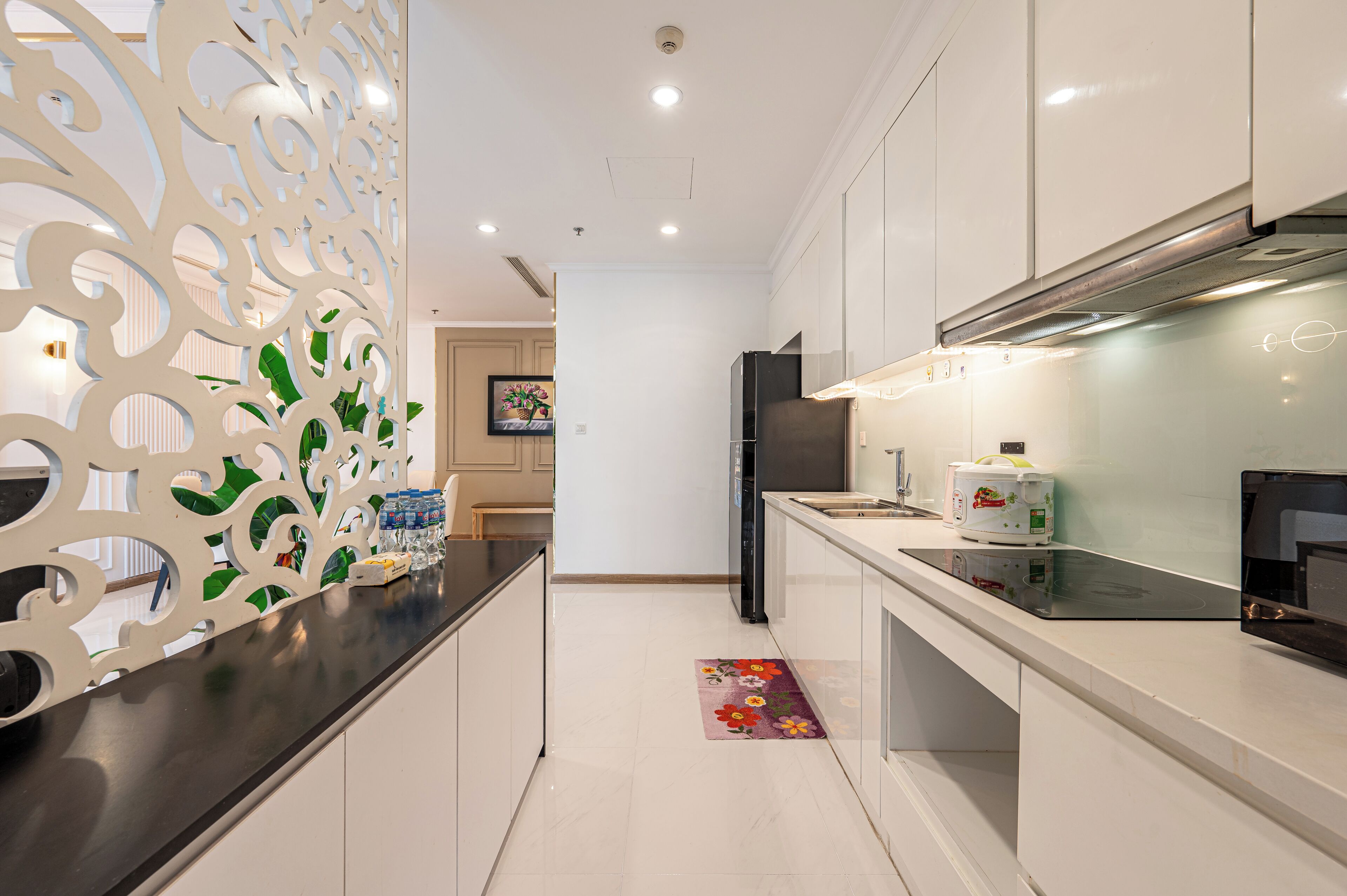 Una cocina moderna con armarios blancos, encimera negra y campana extractora de acero inoxidable.