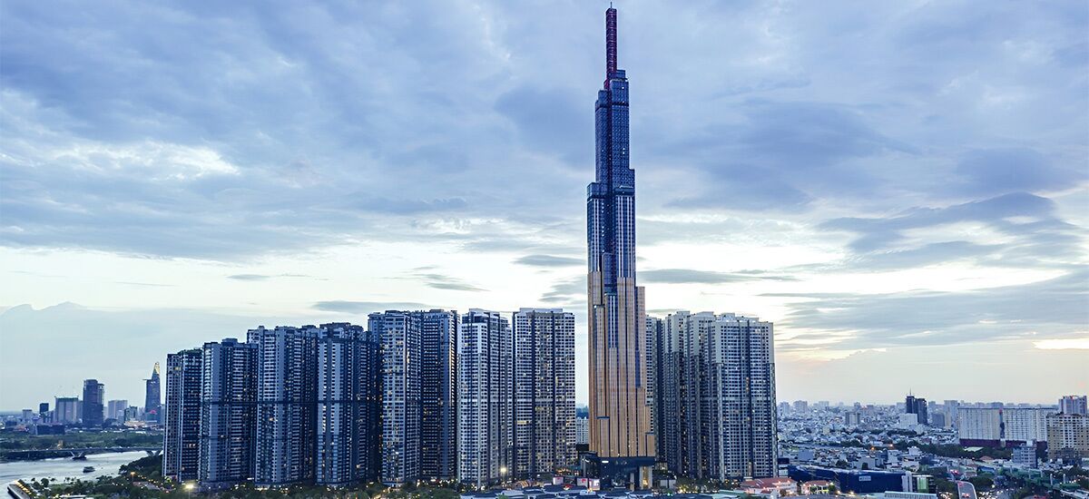 A high-rise building with a distinctive tapering design, surrounded by other high-rise buildings in a cityscape.
