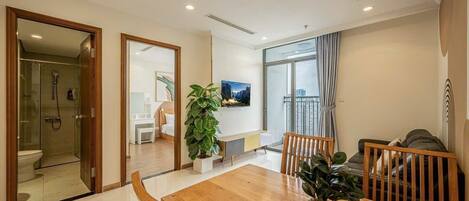 A modern living room with a wooden dining table, a sofa, and a large window.