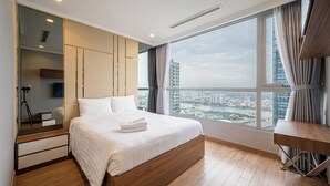 A modern hotel room with a large bed, a desk, and a view of the cityscape. - Vinhomes Cozy Apartment (Ho Chi Minh City)