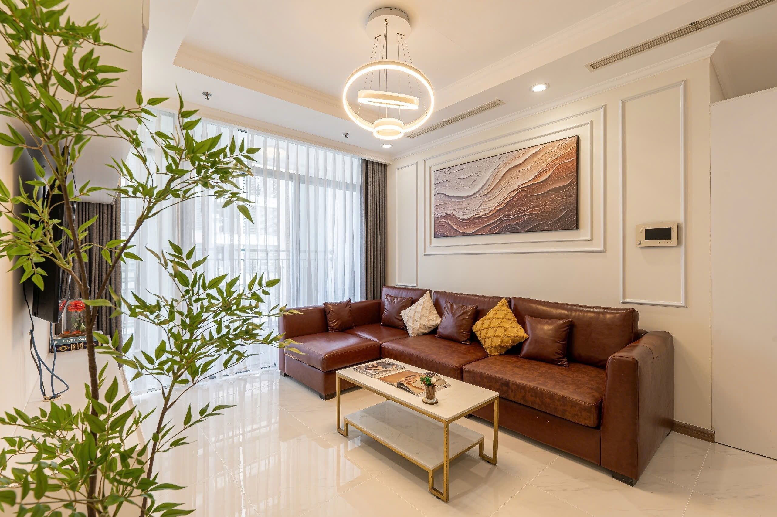 A modern living room with a brown leather sofa, a coffee table, and a large window with blinds.