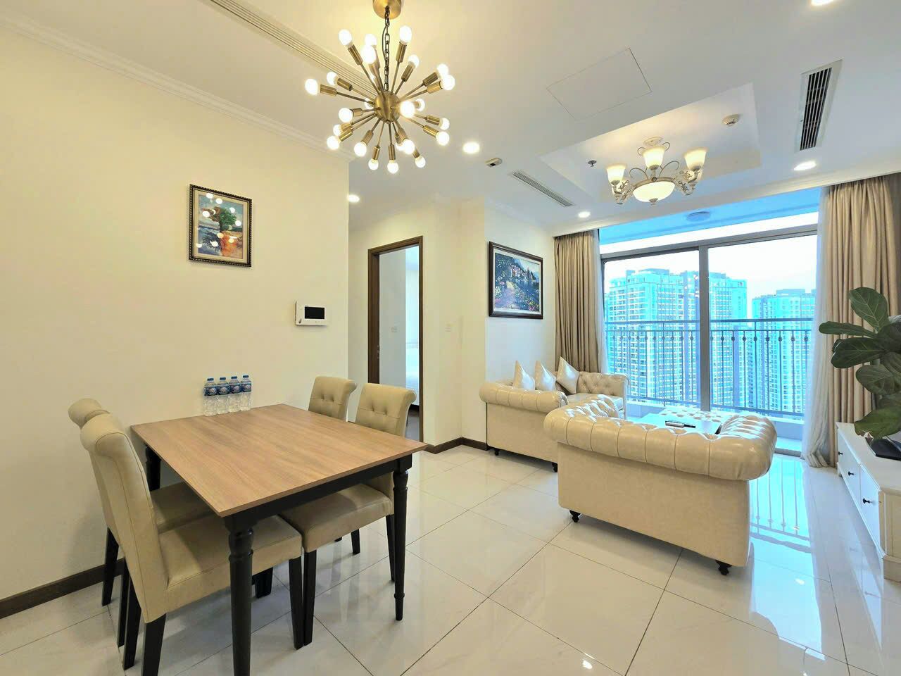 A modern living room with a dining area, large windows, and a view of the cityscape.