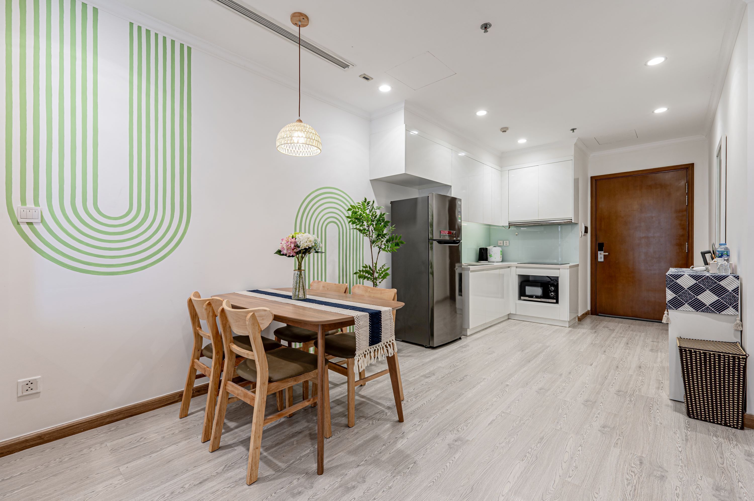 A modern kitchen with a stainless steel refrigerator, wooden dining table, and chairs.