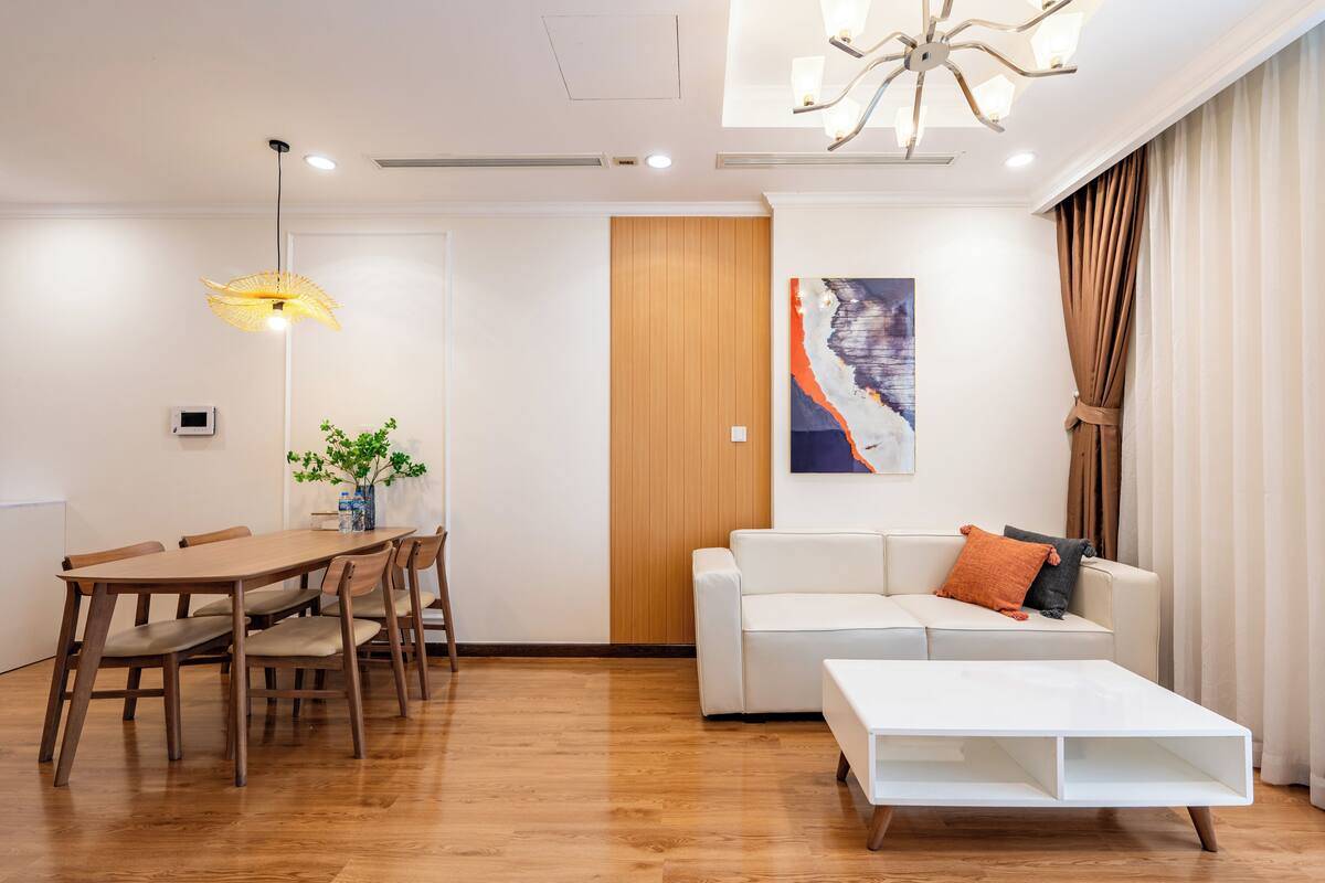A modern living room with a wooden dining table, white sofa, and a white coffee table.