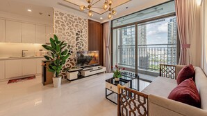 A modern living room with a sofa, coffee table, TV, and a balcony with a city view. - Vinhomes Cozy Apartment (Ho Chi Minh City)