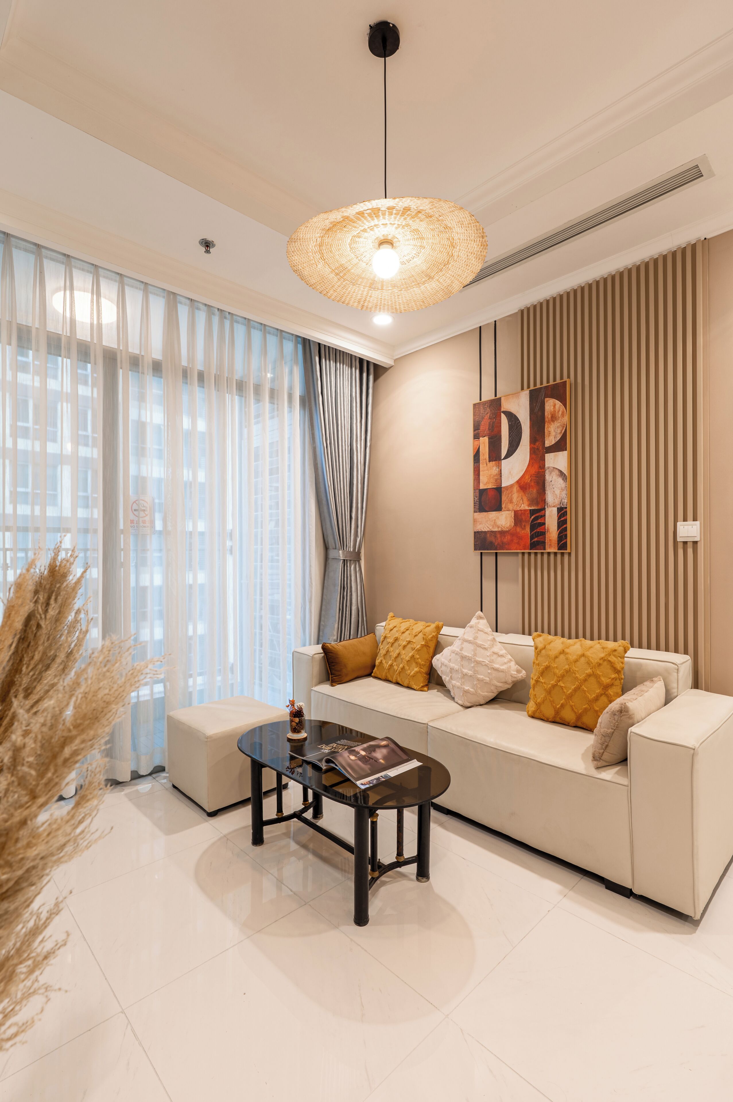 A modern living room with a sofa, a coffee table, and a hanging light fixture.