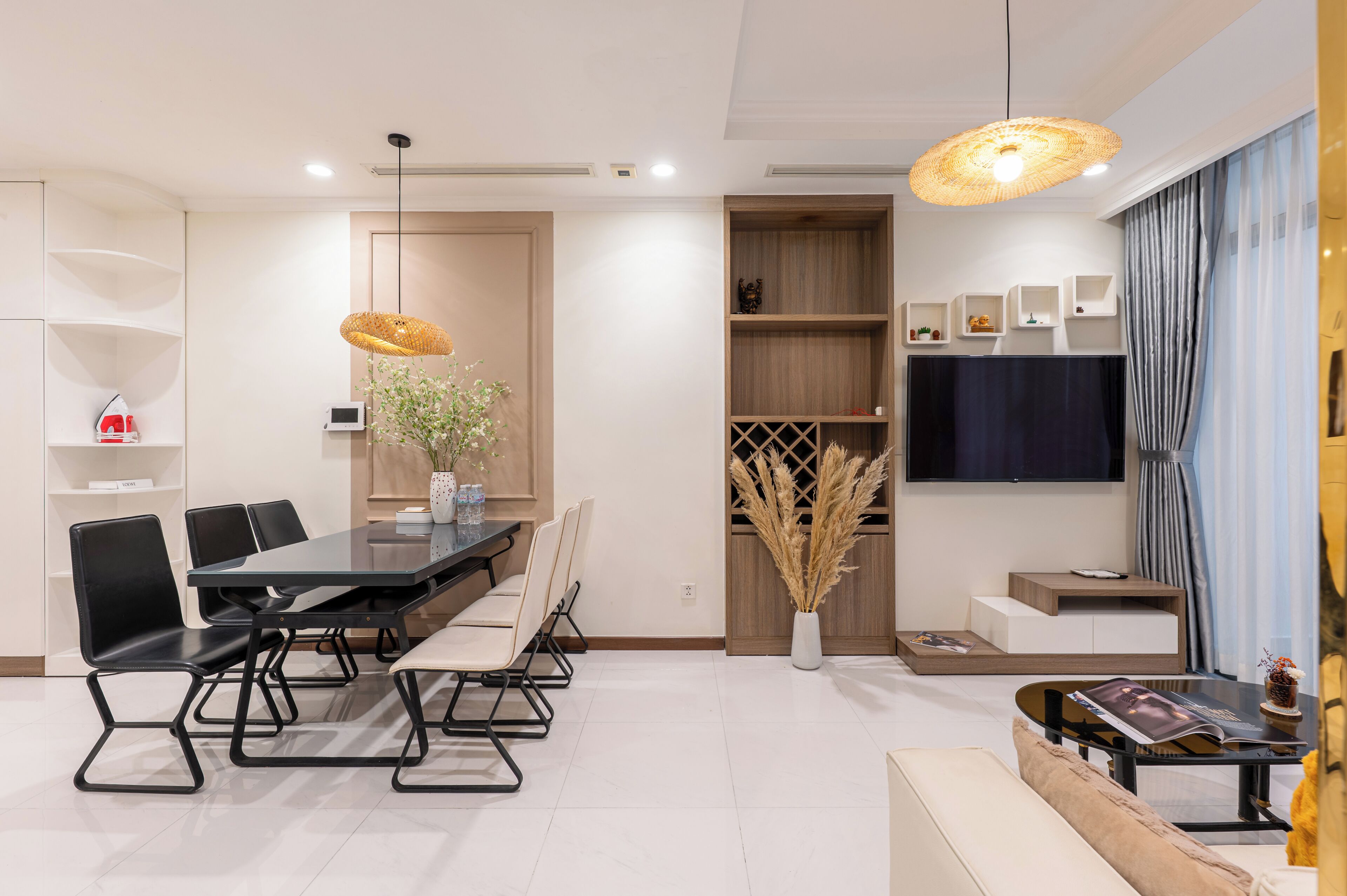 A modern living room with a dining area, a TV, and a large window with curtains.