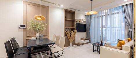 A modern living room with a dining area, a sofa, and a TV.