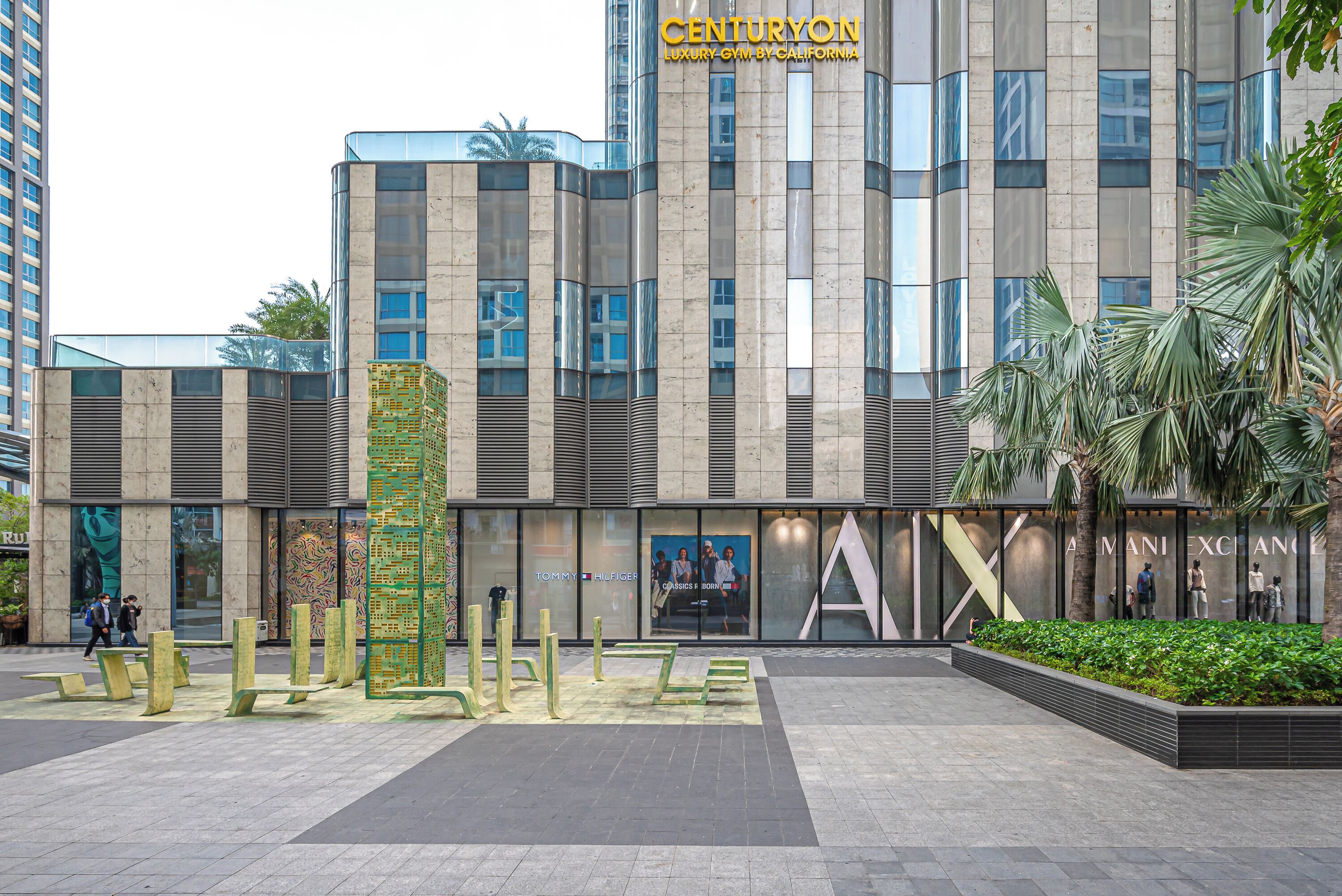 A modern building with a prominent 'CENTURYON' sign, featuring a glass facade and a landscaped plaza with benches.