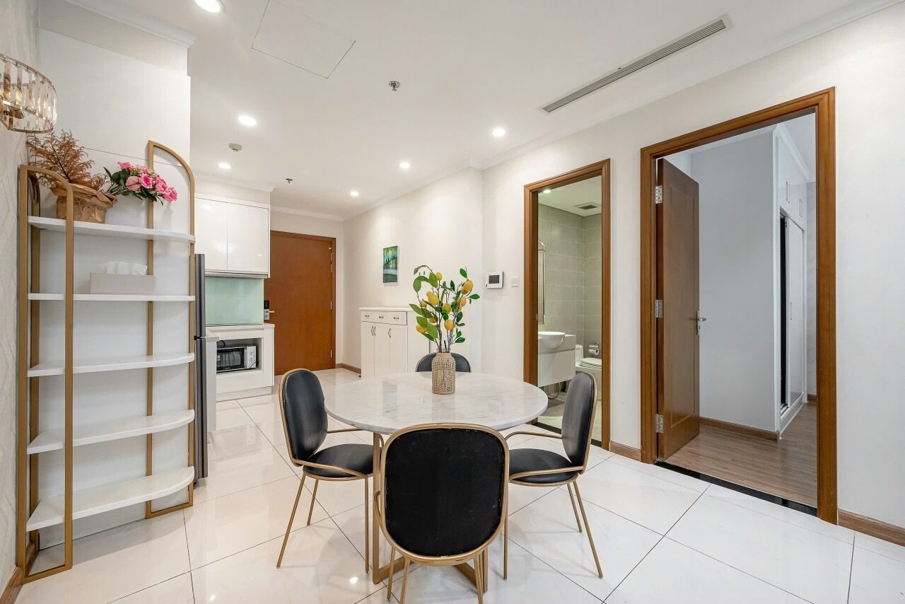 Un coin repas moderne avec une table ronde, quatre chaises et un vase rempli de fleurs.
