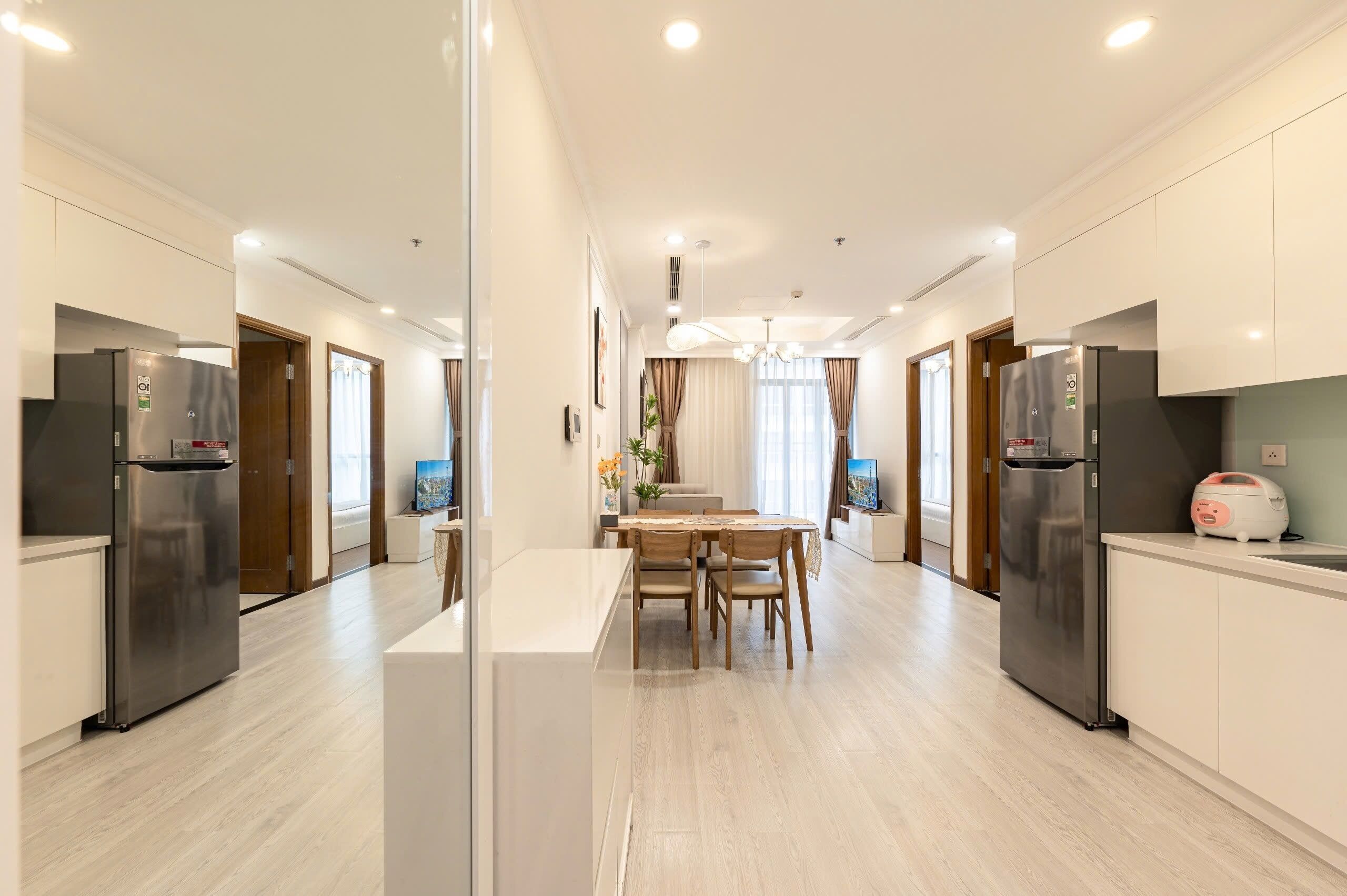 Een moderne keuken met roestvrijstalen apparatuur, een eethoek met een tafel en stoelen, en een hal met deuren die leiden naar andere kamers.