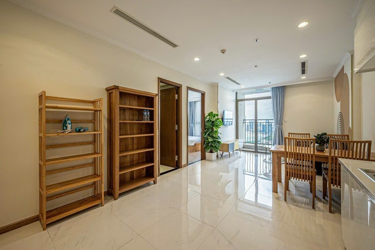 Un'ampia camera d'hotel con un letto grande, un armadio in legno, un'area pranzo con tavolo e sedie, e un balcone con vista.