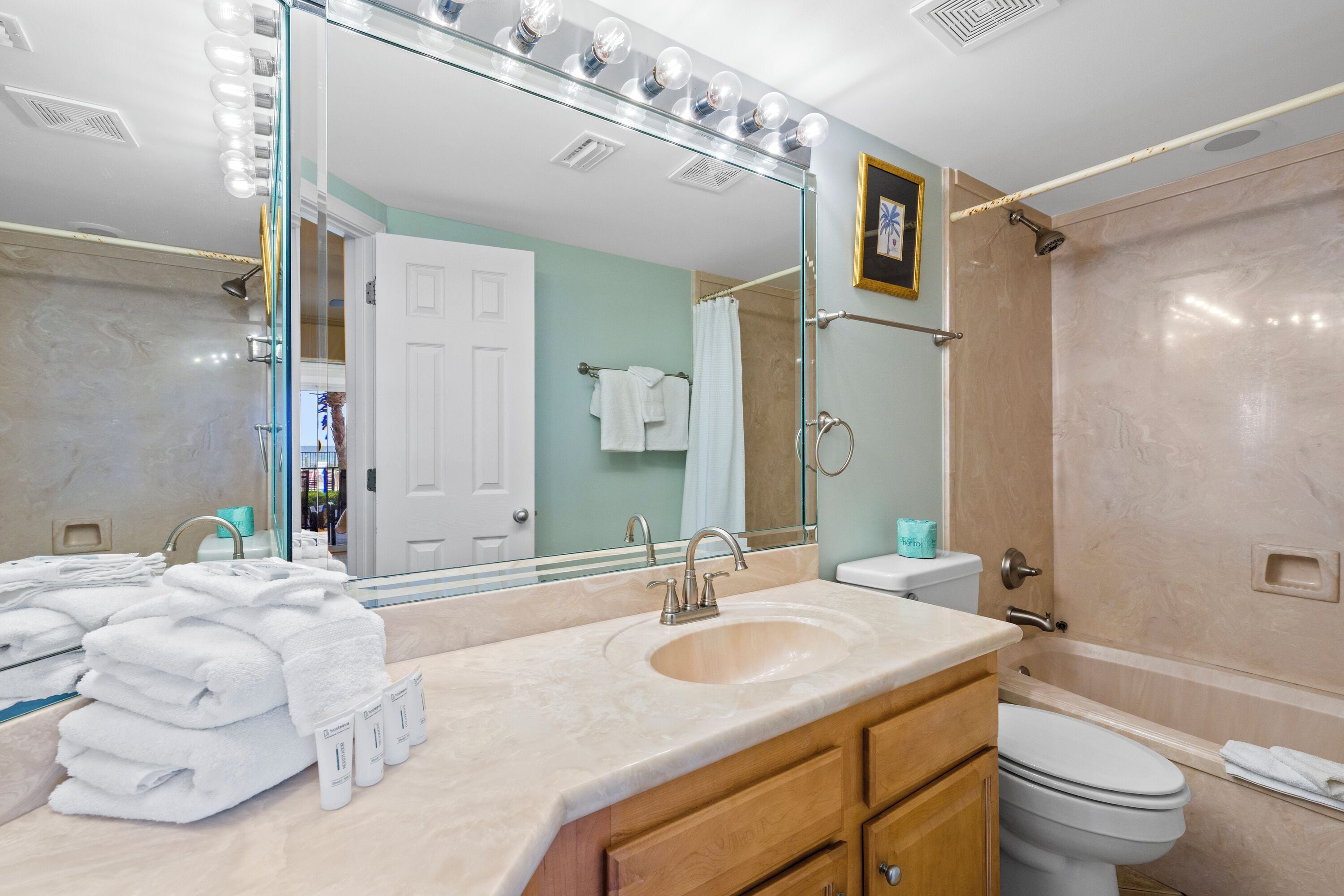 A bathroom with a sink, mirror, and shower.