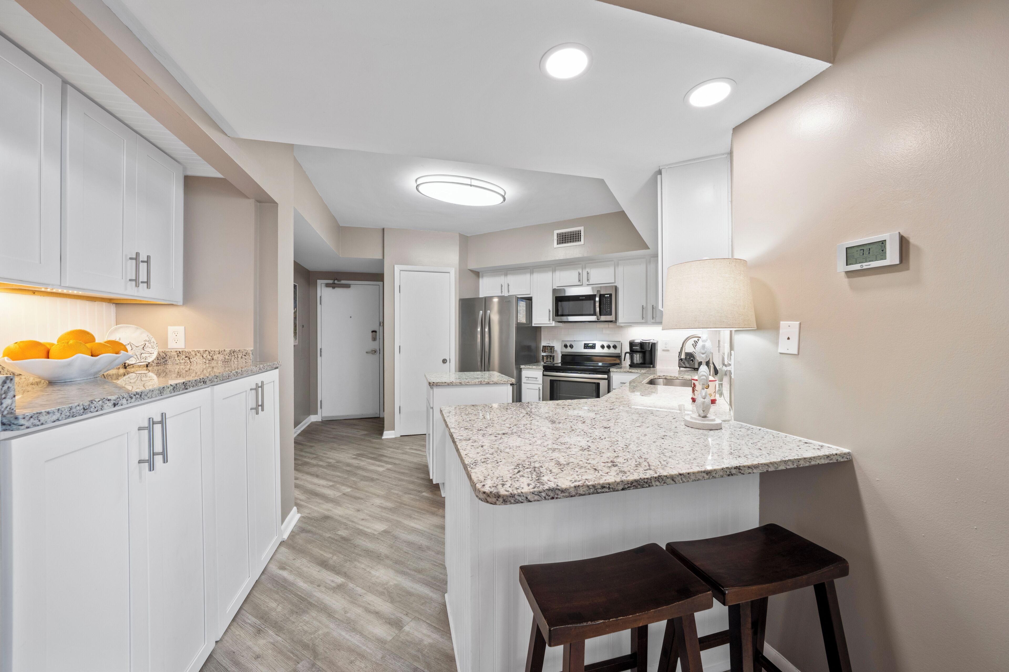 A modern kitchen with white cabinets, granite countertops, and stainless steel appliances.