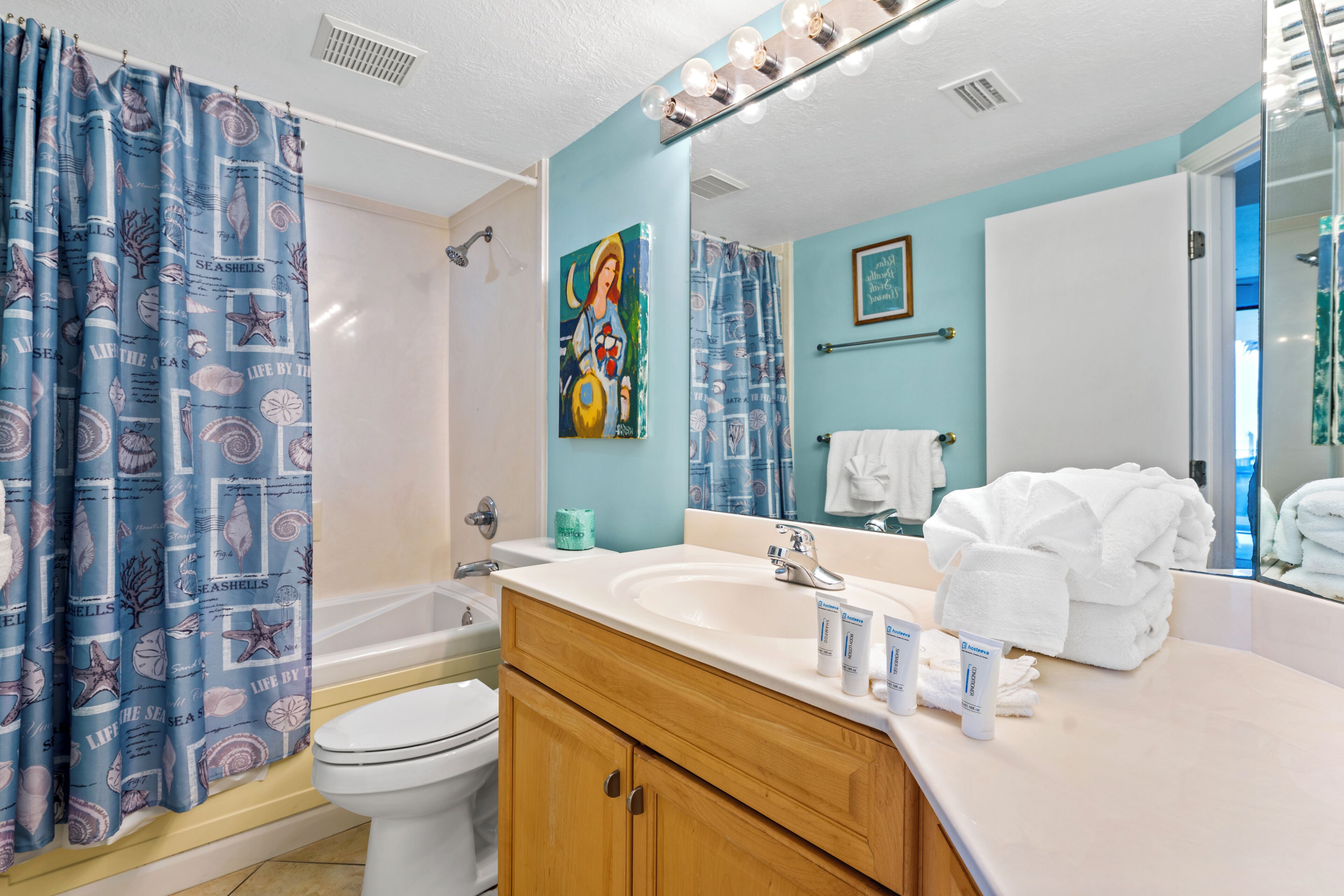 A bathroom with a bathtub, toilet, sink, and a mirror with a towel rack.