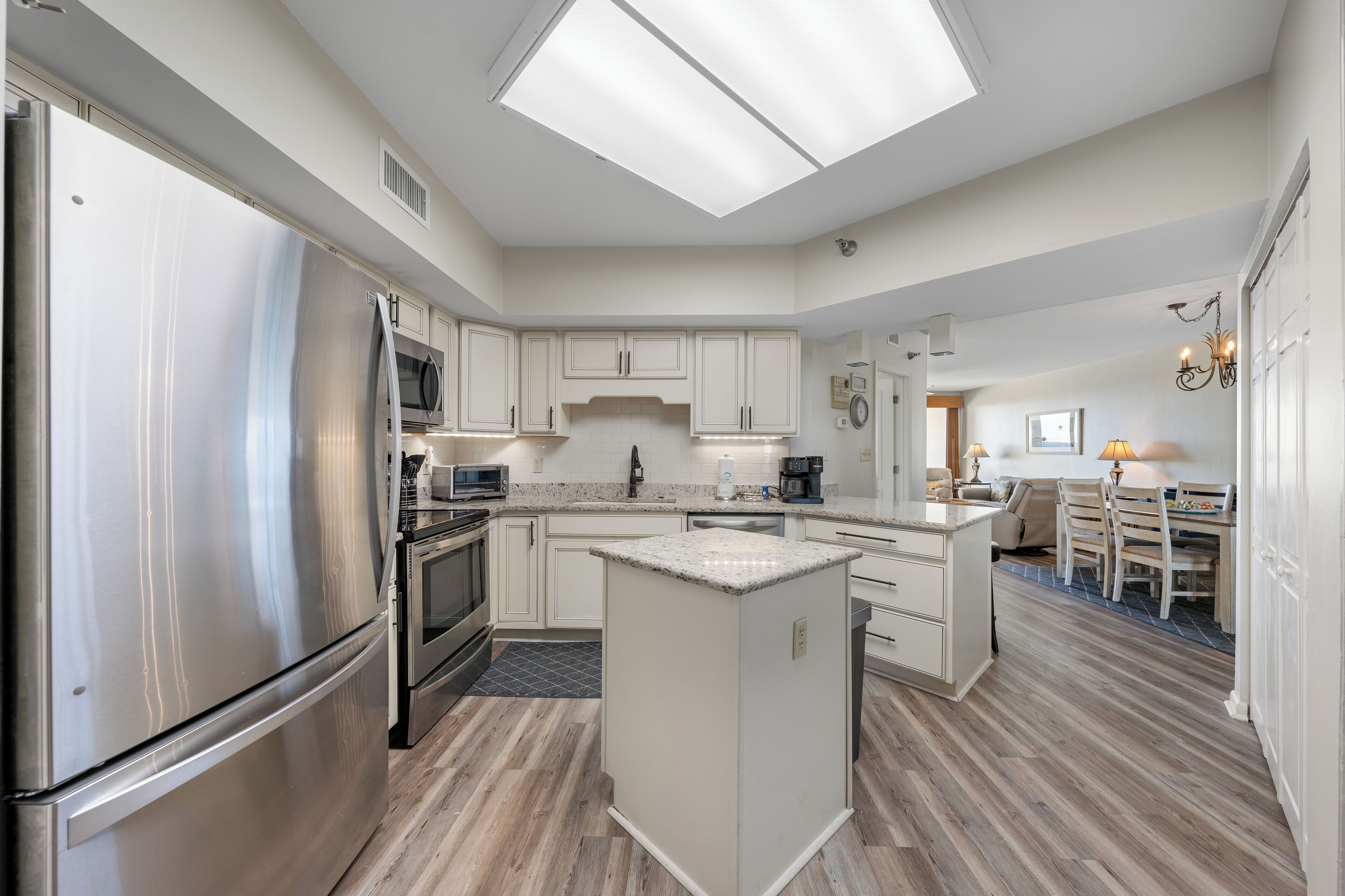 A modern kitchen with a stainless steel refrigerator, built-in oven, microwave, and a central island.