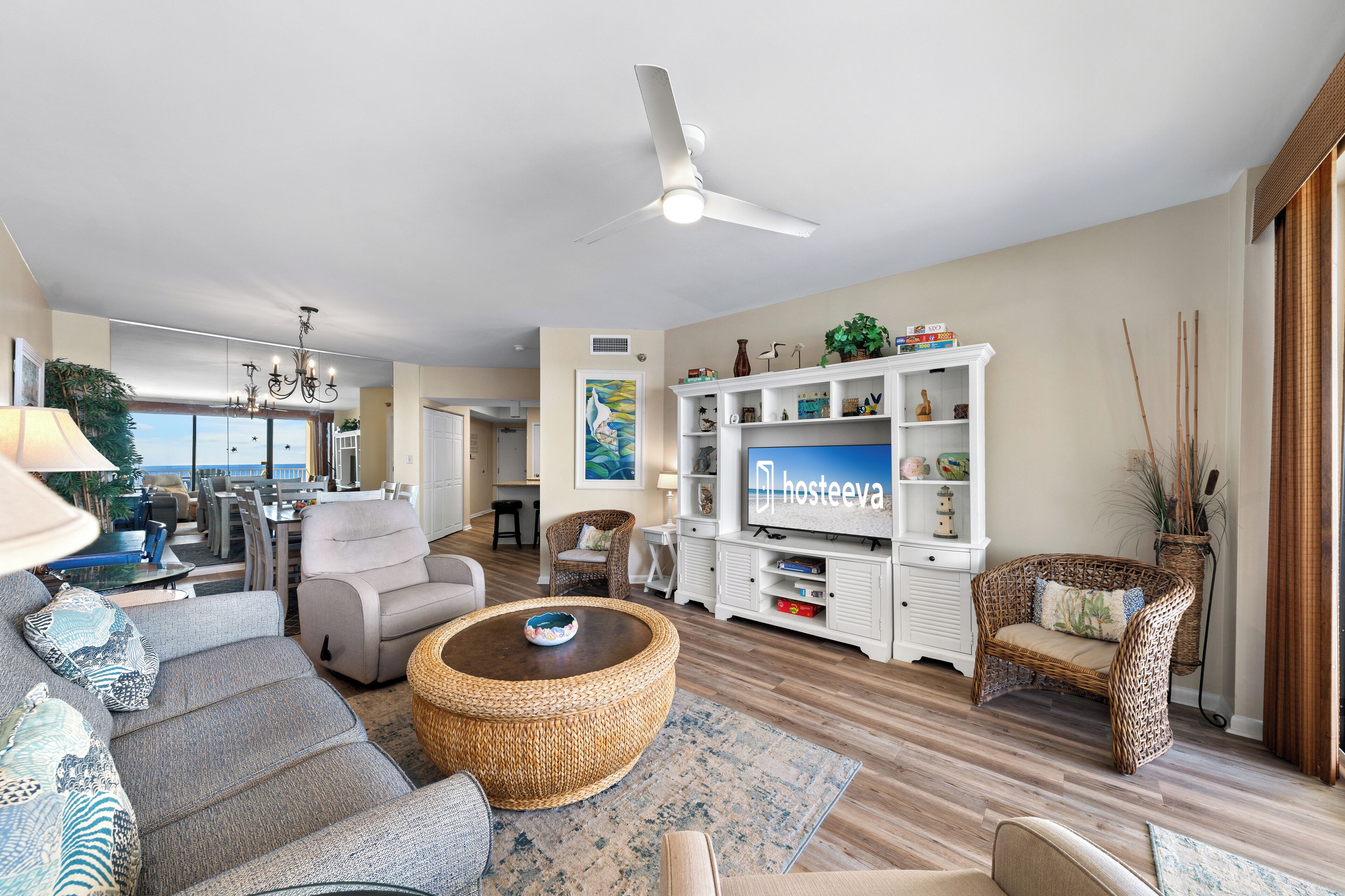 A modern living room with a flat-screen TV, comfortable seating, and a view to the outside.