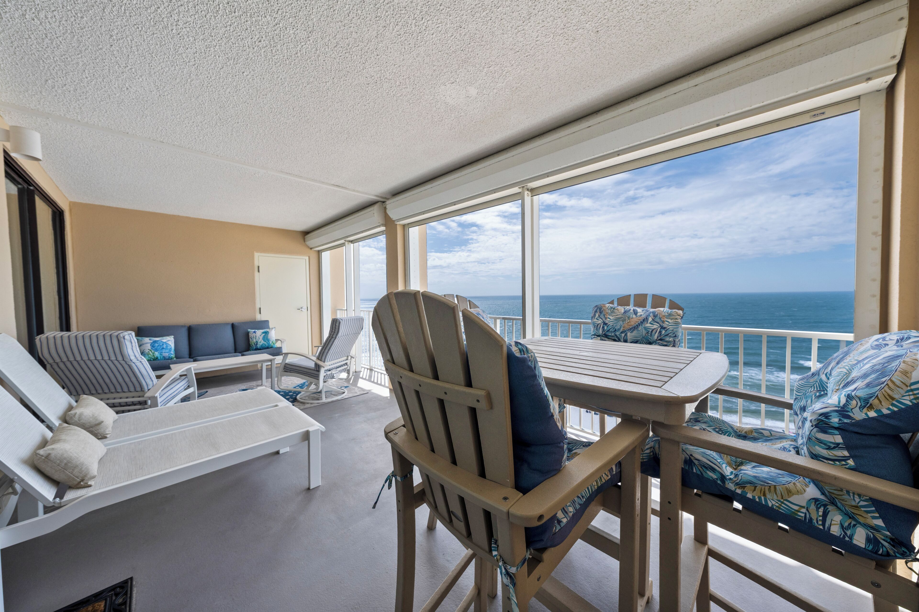 Een zonnige kamer met uitzicht op zee, met een tafel, stoelen en een bank.