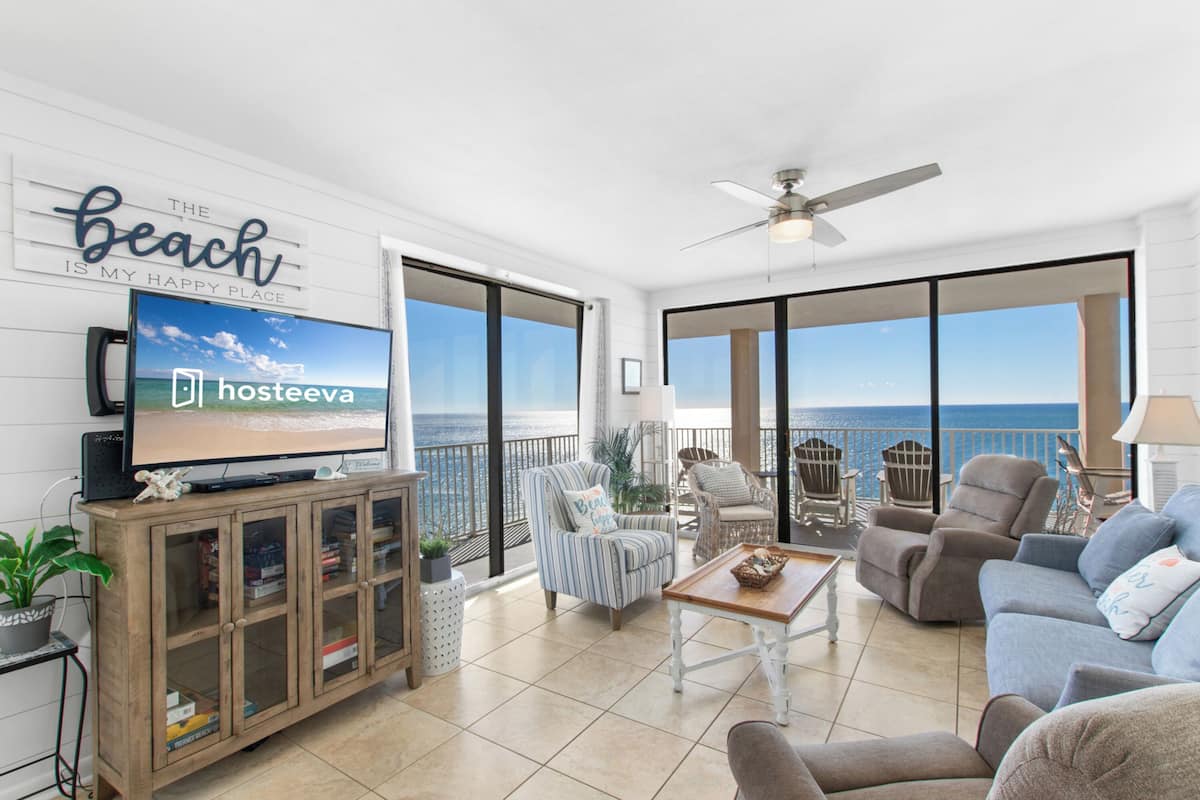 Un vaste balcon offrant une vue sur l’océan, aménagé avec un canapé, des fauteuils et une table basse.