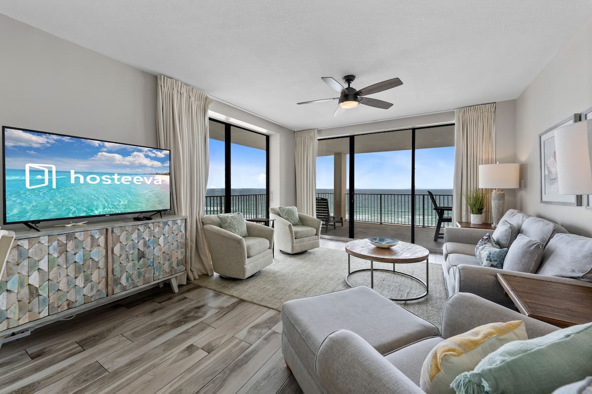 Un salon moderne avec une télévision, des canapés, une table basse et un balcon offrant une vue agréable.