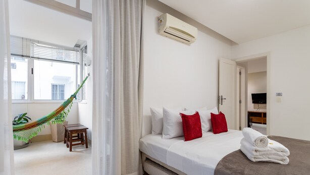 A hotel room with a bed, a hammock, a small table, and a TV in the corner. - 4 Minutes From Copacabana Beach Nsc205 (Rio de Janeiro)