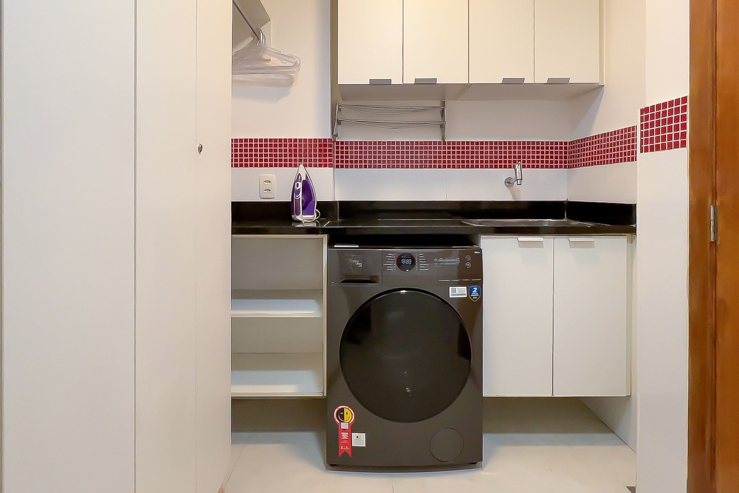 Una cocina compacta con lavadora, un lavamanos y una estufa.