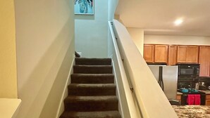 A staircase leading to a kitchen with wooden cabinets and a refrigerator.