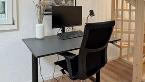 Een modern bureau met een computer, een stoel en een decoratieve vaas.