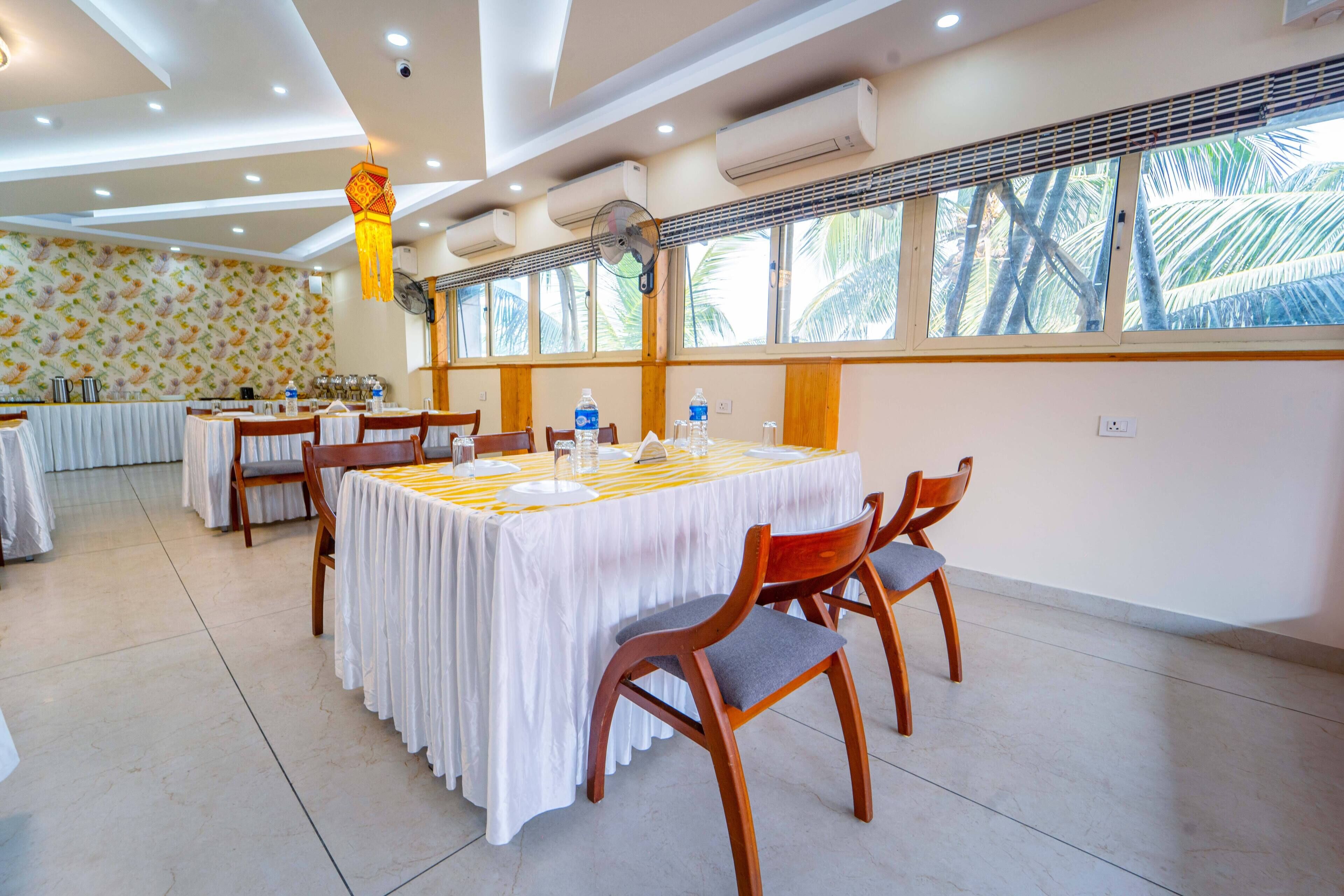 Un salón de conferencias con mesas redondas, sillas y una lámpara colgante decorativa.