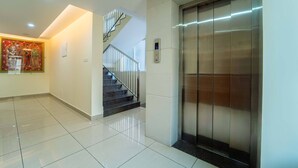 A modern interior with a tiled floor, a staircase with metal railings, and a wall-mounted elevator. - Treebo Sree Varshavilas Regency, 500 Mtrs From Guruvayoor Temple (Chavakkad)